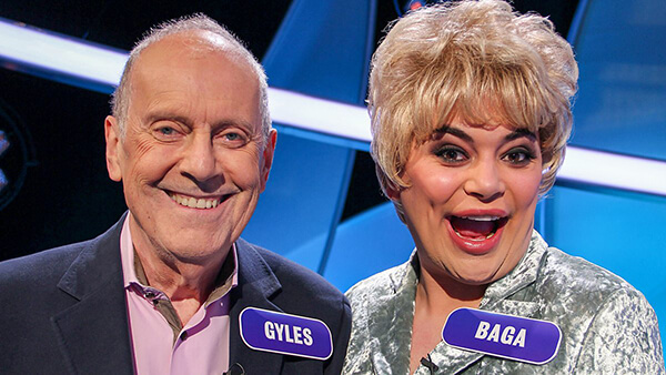 Gyles Brandreth and drag queen Baga Chipz on Pointless Celebrities, smiling and wearing large name tags