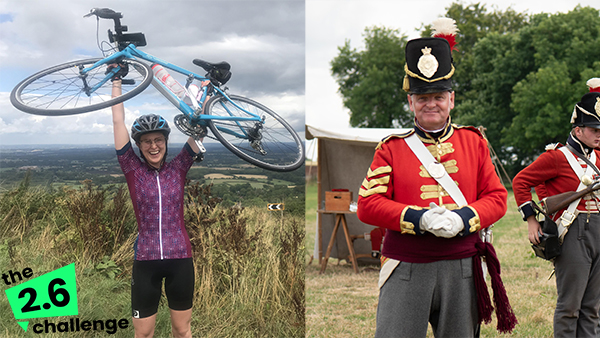 Fundraising Officer Kate Scott in lyrca with a helmet, raising a bicycle above her head, and reenactor Clive Jones, in full Napoleonic era British uniform at Hougoumont